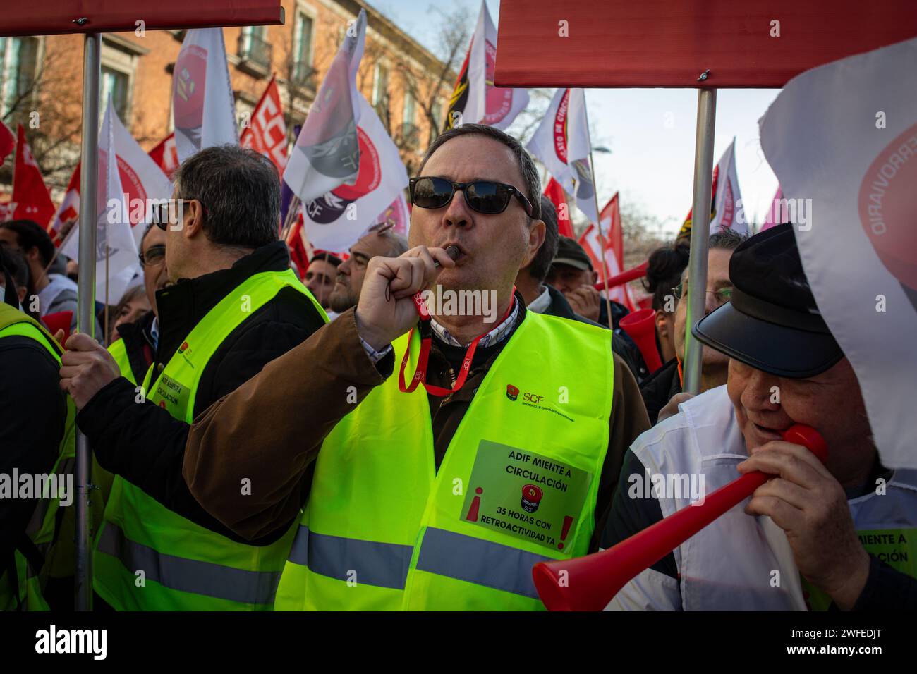 Madrid, Spain. 30th Jan, 2024. A railway protester blows a whistle as another blows a vuvuzela during the rally in front of the Congress of Deputies. The workers' union, Comisiones Obreras, has called a rally in front of the Congress of Deputies to demand the unblocking of the agreements on the elimination of entry categories in Renfe (National Network of Spanish Railways) and on the implementation of the 35-hour day in Adif (railway infrastructure administrator) Credit: SOPA Images Limited/Alamy Live News Stock Photo