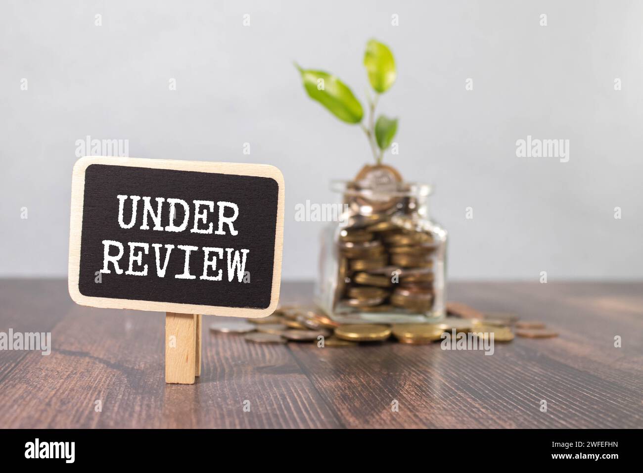 under review. text is written on white paper on a wooden table. Stock Photo