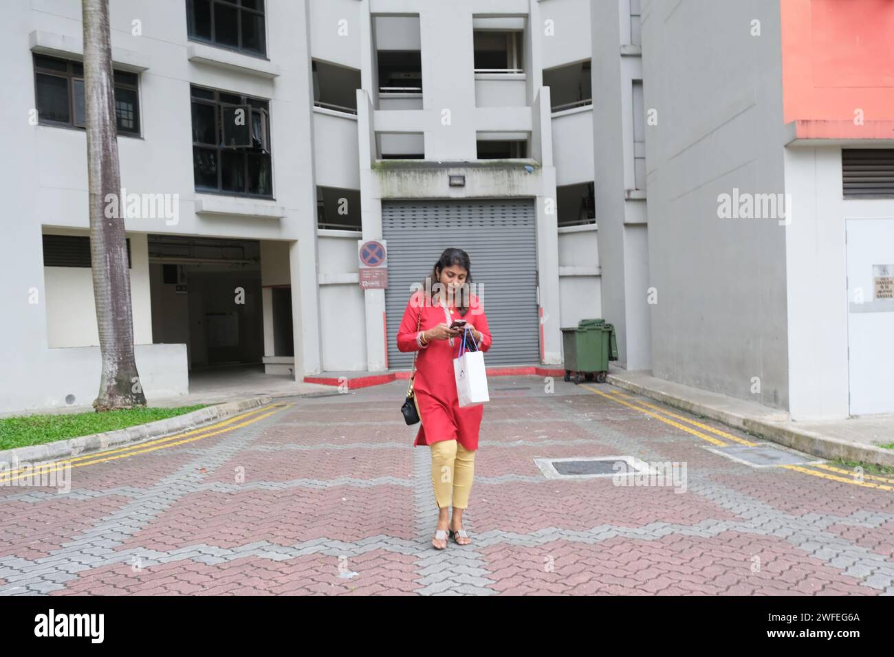 Ethnic Indian woman walks out of an HDB block in Sengkang, northeastern Singapore Stock Photo