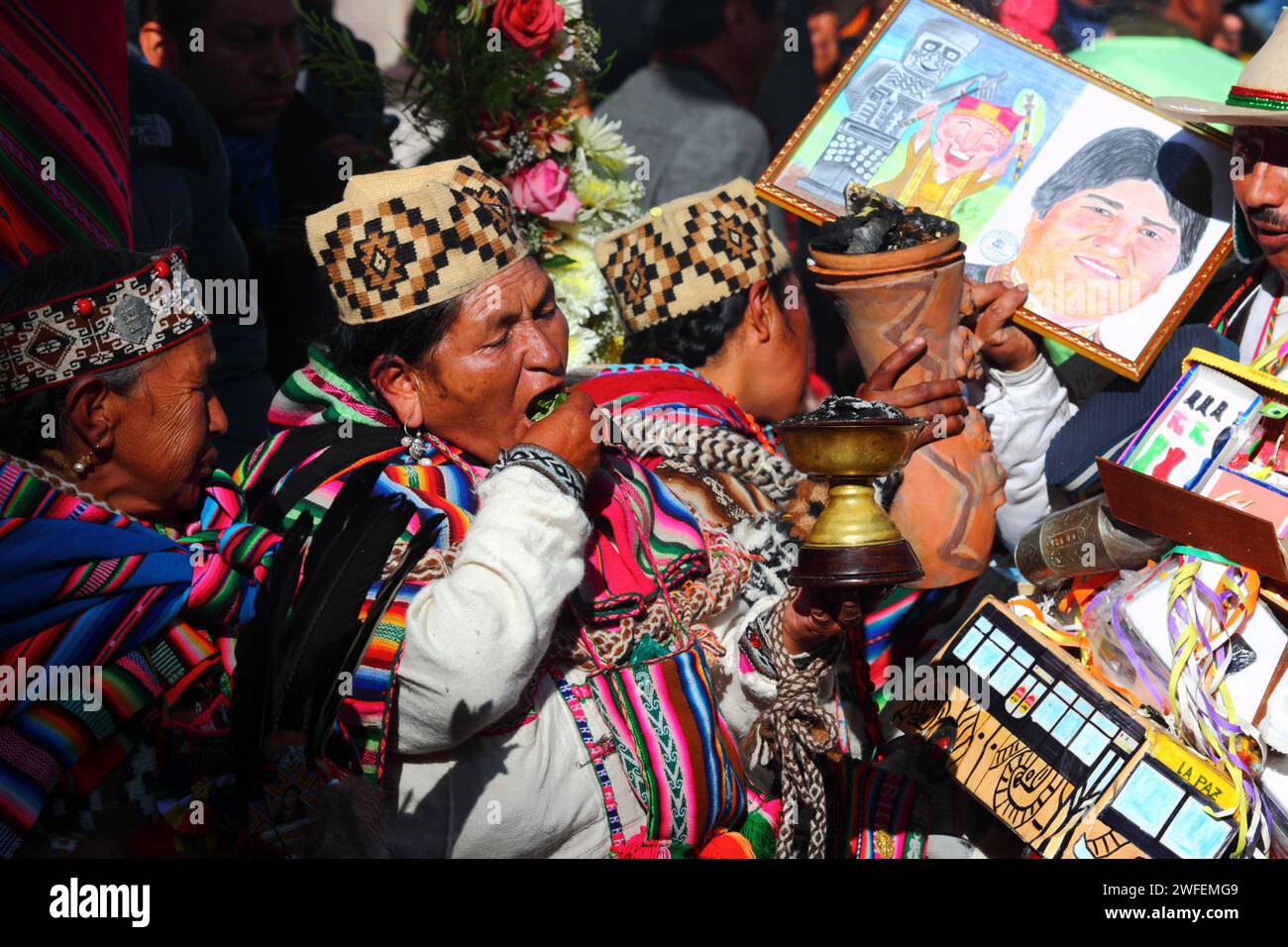 La Paz, BOLIVIA; 24th January 2015. A female shaman chewing coca leaves stands next to a man holding a picture of Bolivian president Evo Morales at an event to mark the start of the Alasitas festival in La Paz. The drawing was given to Evo Morales as a gift after this images was taken. Stock Photo