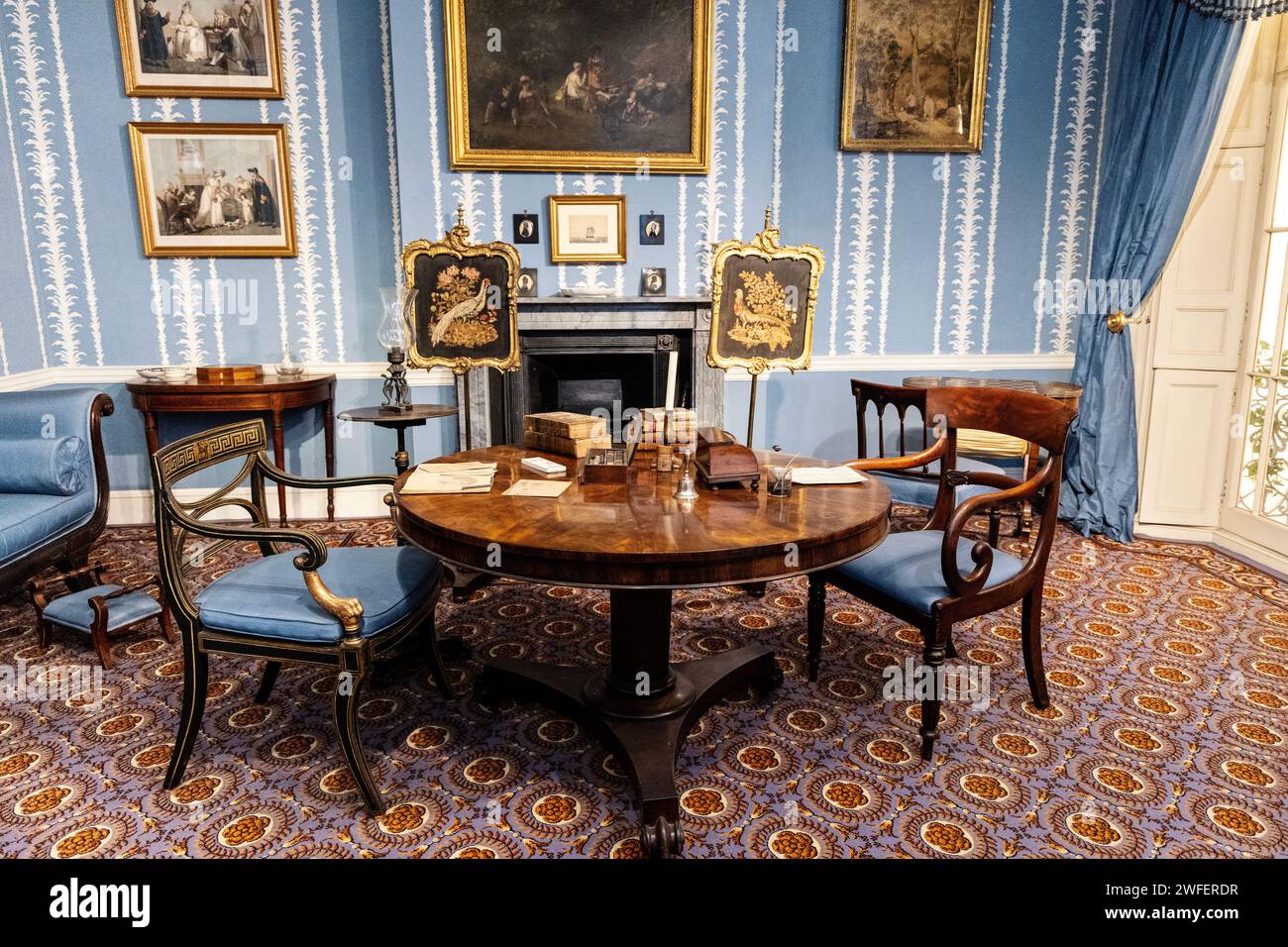 An 1830s drawing room with round table and armchairs Stock Photo