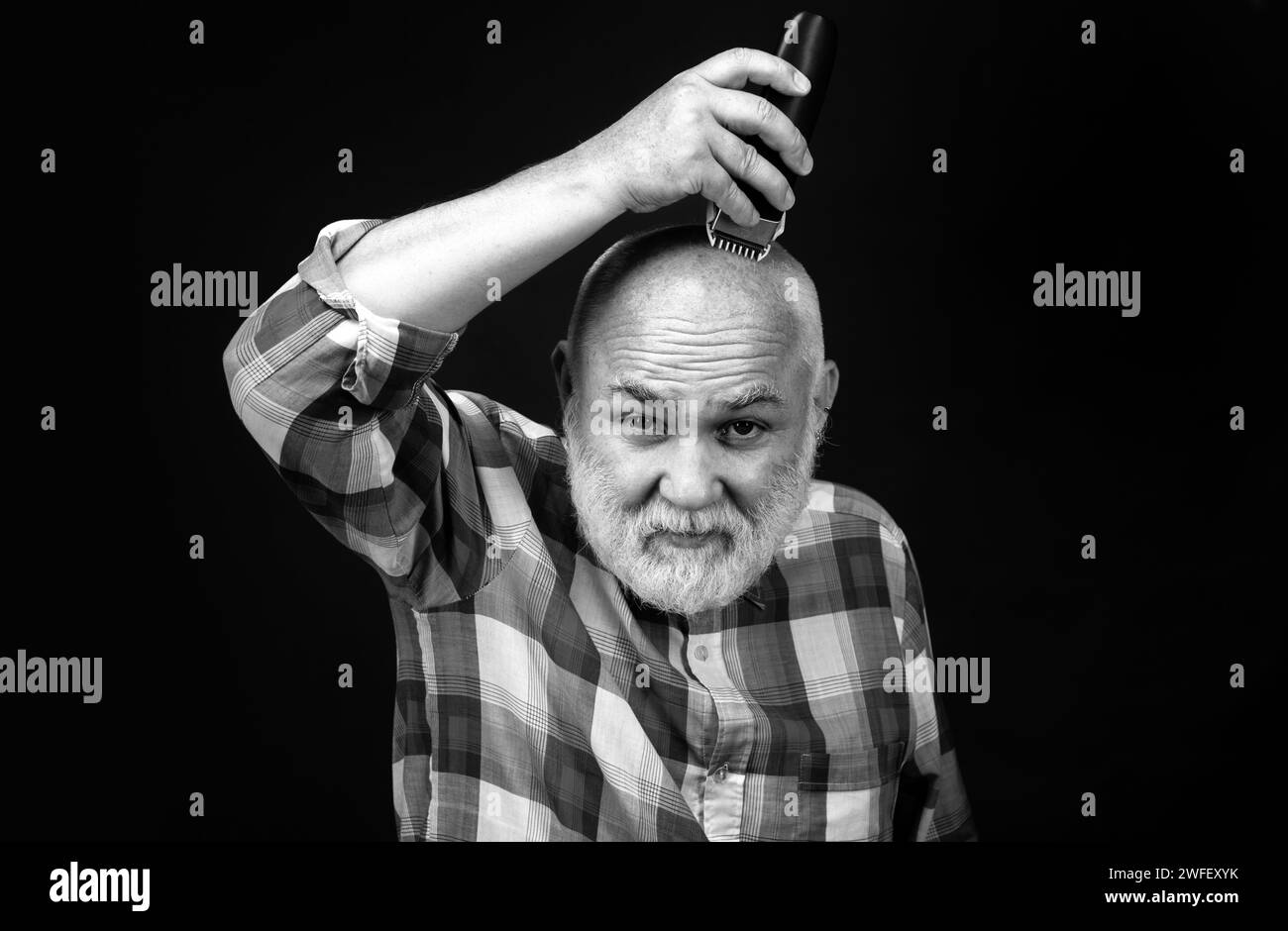 Old man with hair clipper isolated on black. Bald man hairclipper, Mature baldness and hair loss concept. Stock Photo