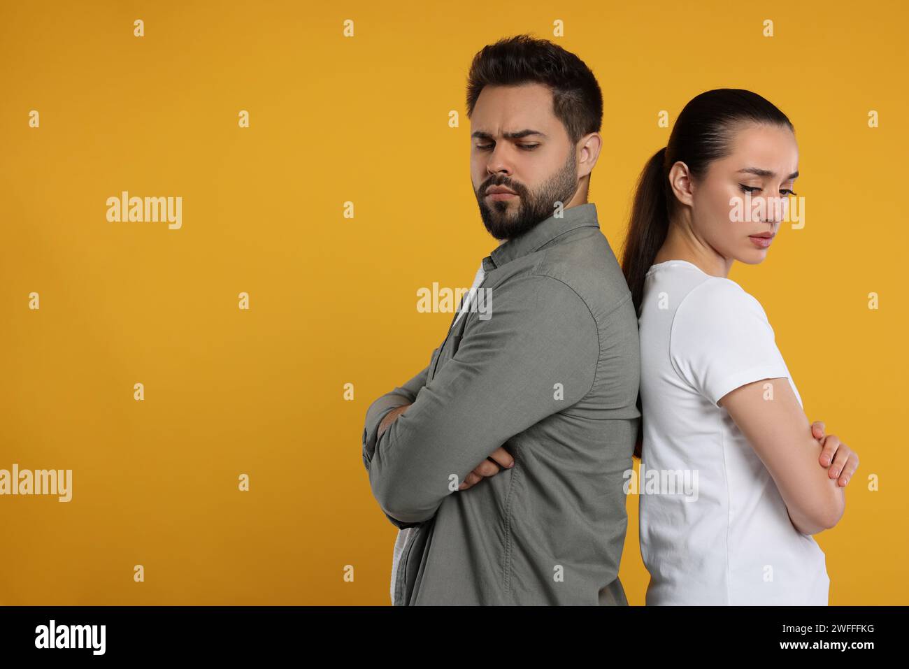 Resentful couple with crossed arms on orange background, space for text Stock Photo