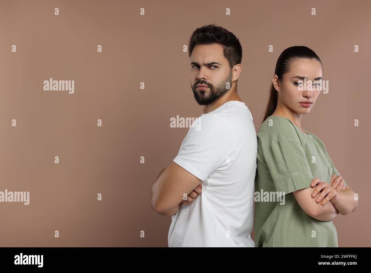 Resentful couple with crossed arms on brown background, space for text Stock Photo