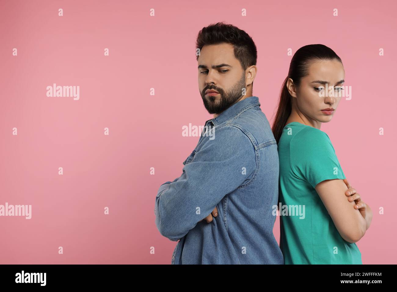 Resentful couple with crossed arms on pink background, space for text Stock Photo