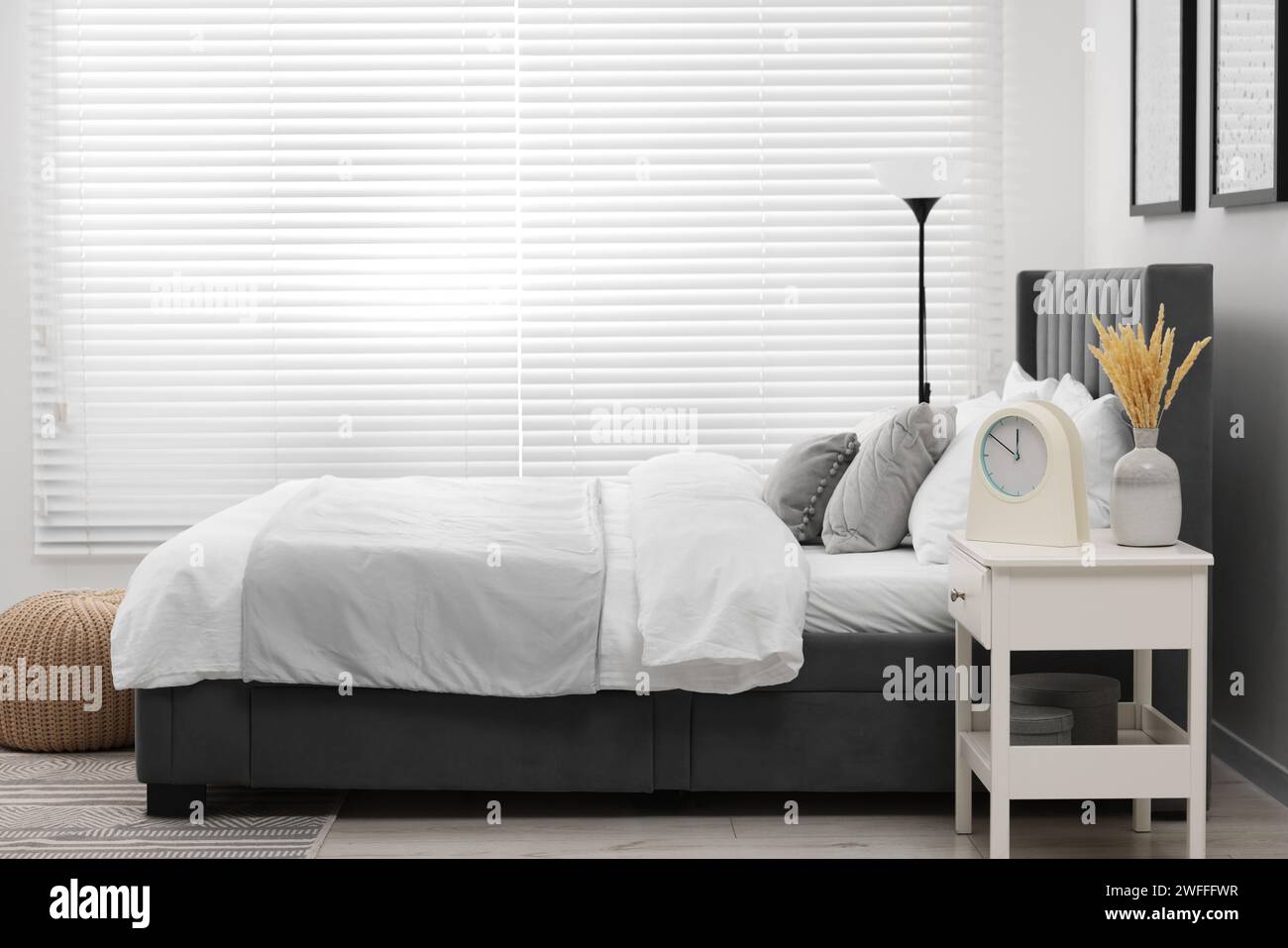 Stylish bedroom interior with large bed, bedside table and lamp Stock