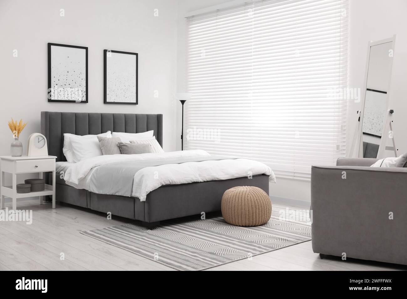 Stylish bedroom interior with large bed, bedside table and lamp Stock