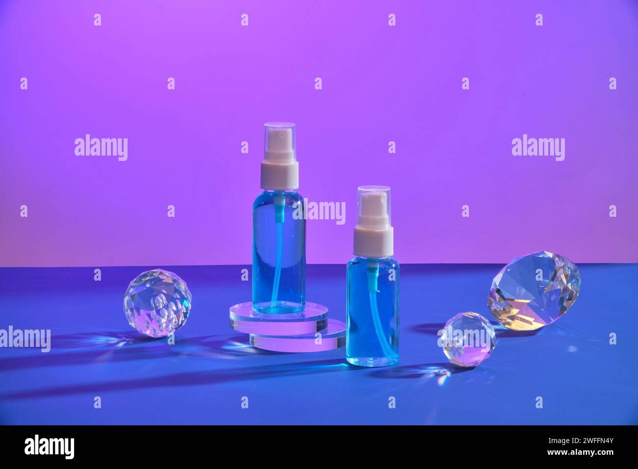 Unlabeled mist spray bottles standing on round transparent podiums