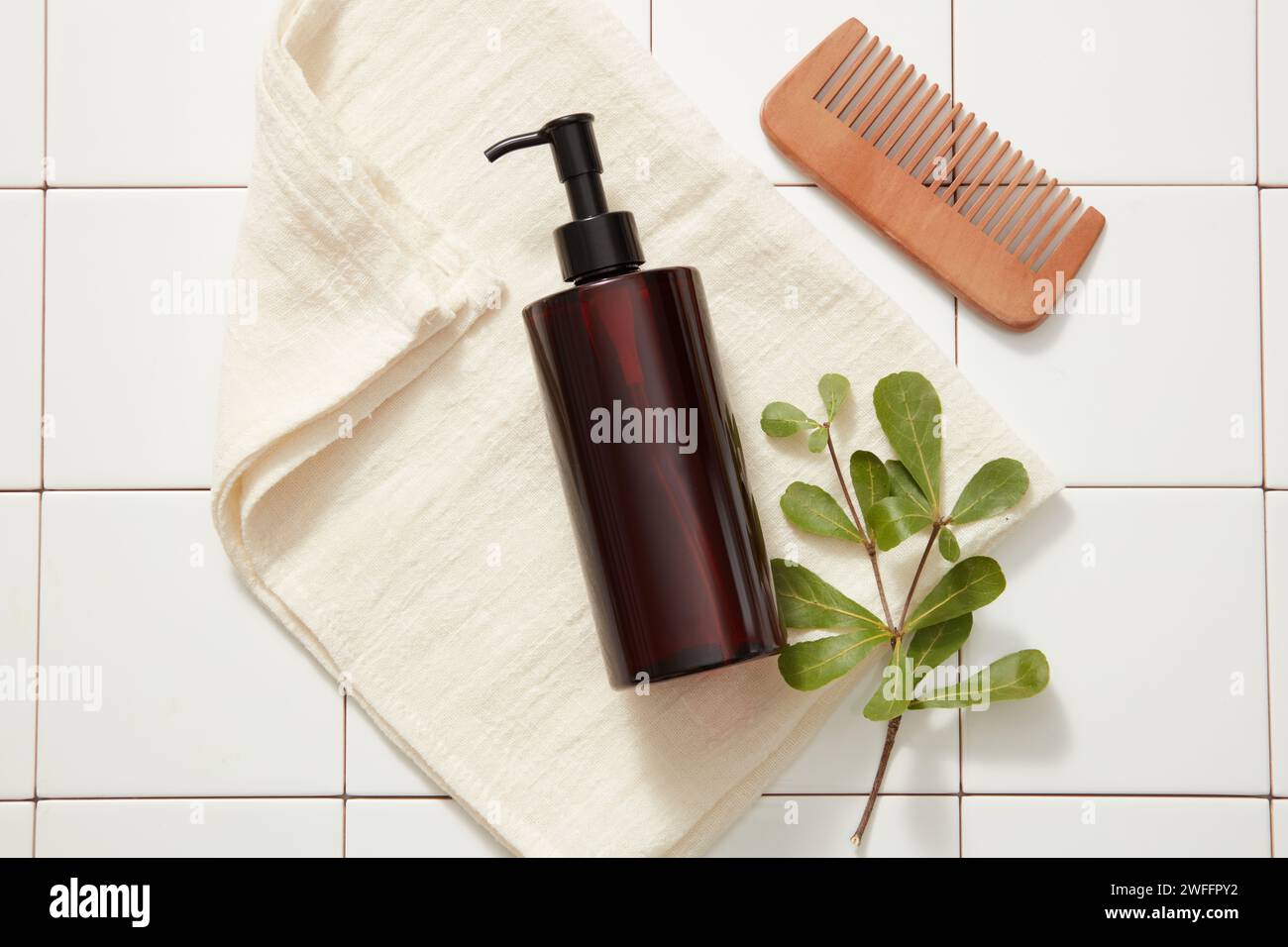 A pump bottle dispenser without label put on a towel with green leaves ...