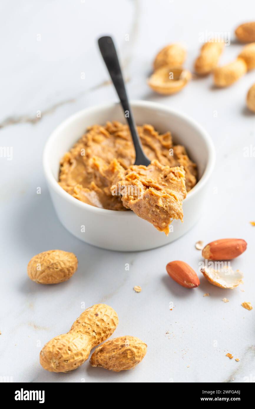 Bowl with homemade crunchy peanut butter and heap of nuts Stock Photo