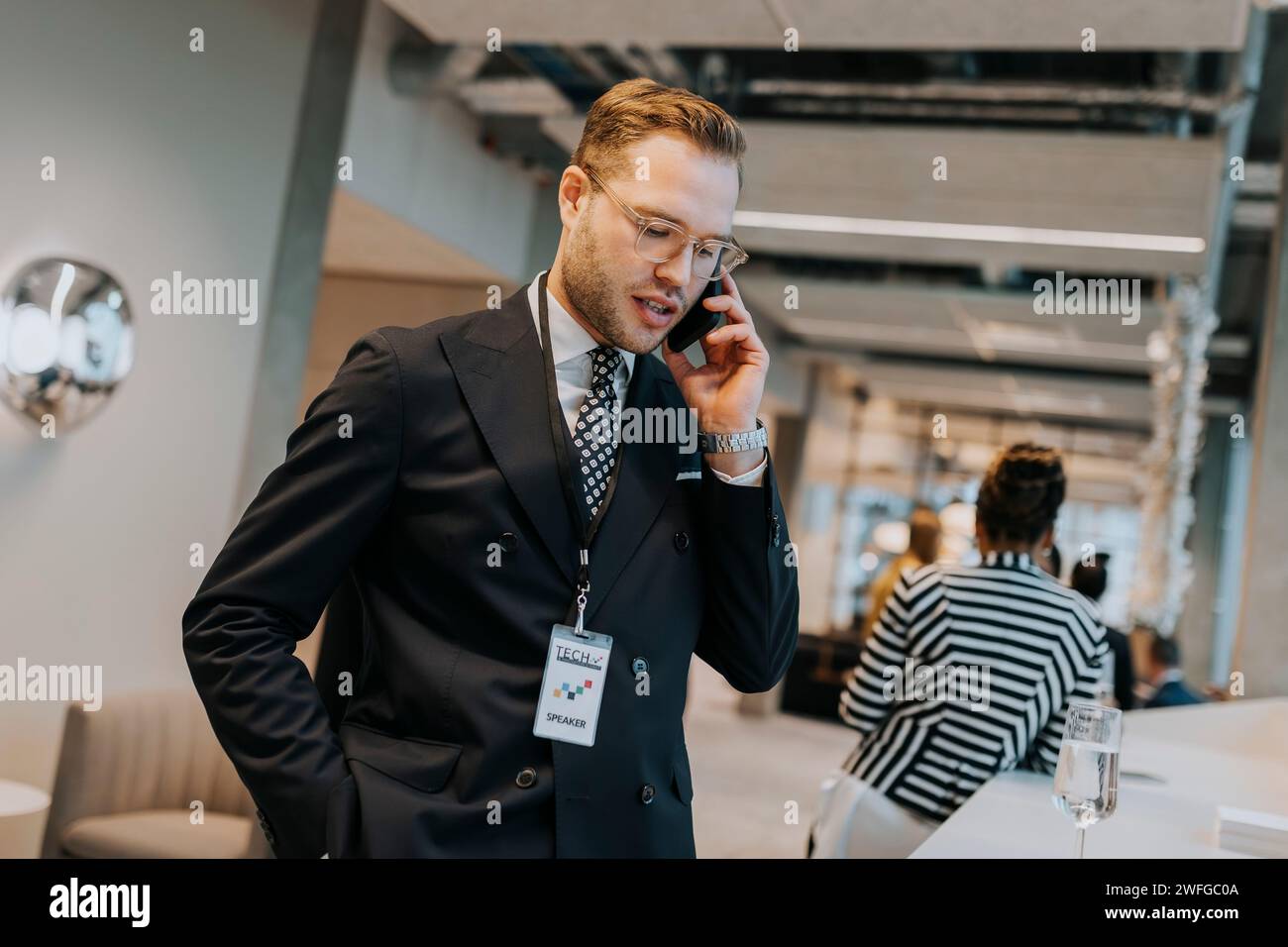 Young businessman talking on mobile phone during networking conference Stock Photo