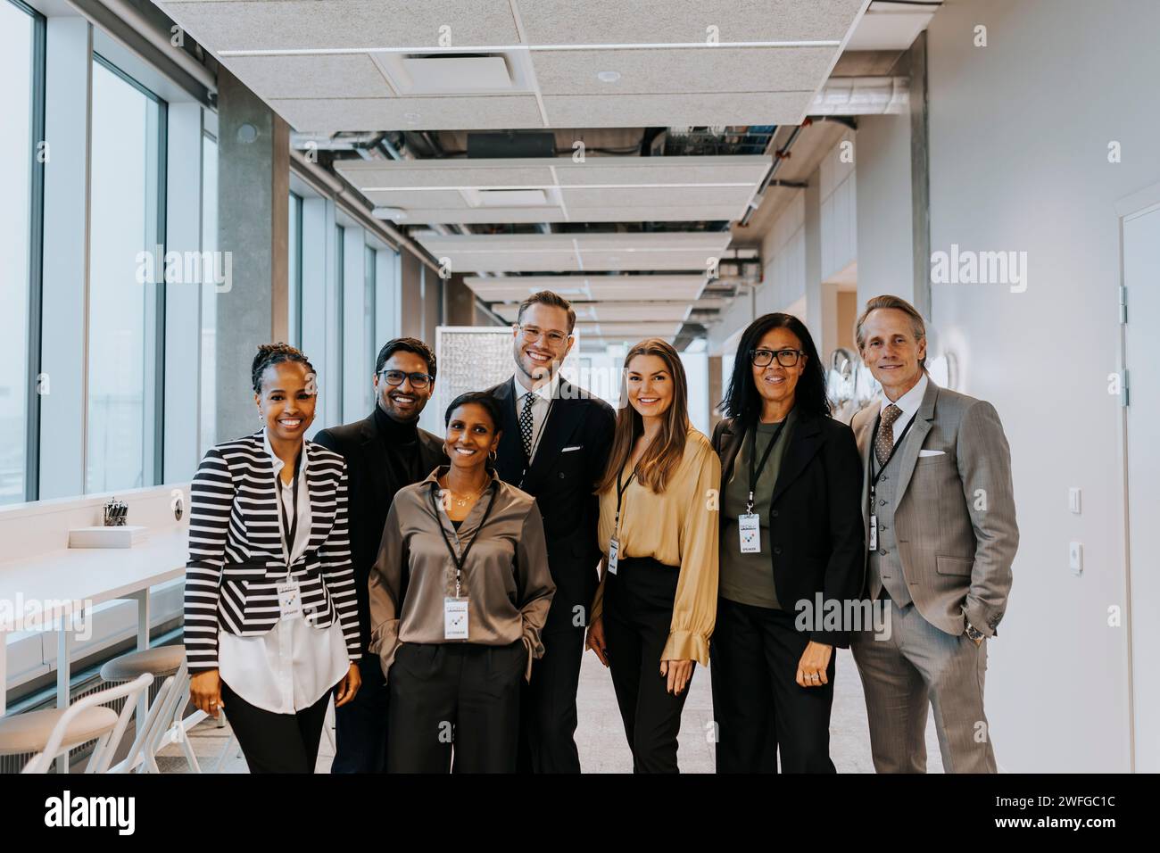 Portrait of smiling multiracial colleagues standing in corridor Stock Photo