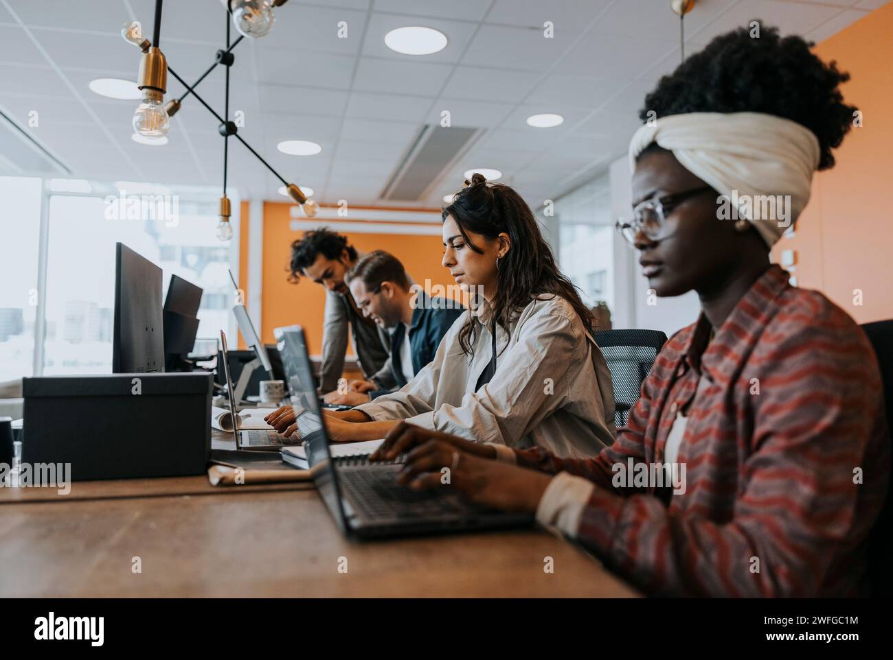 Business colleagues using laptops while working at desk in office Stock Photo