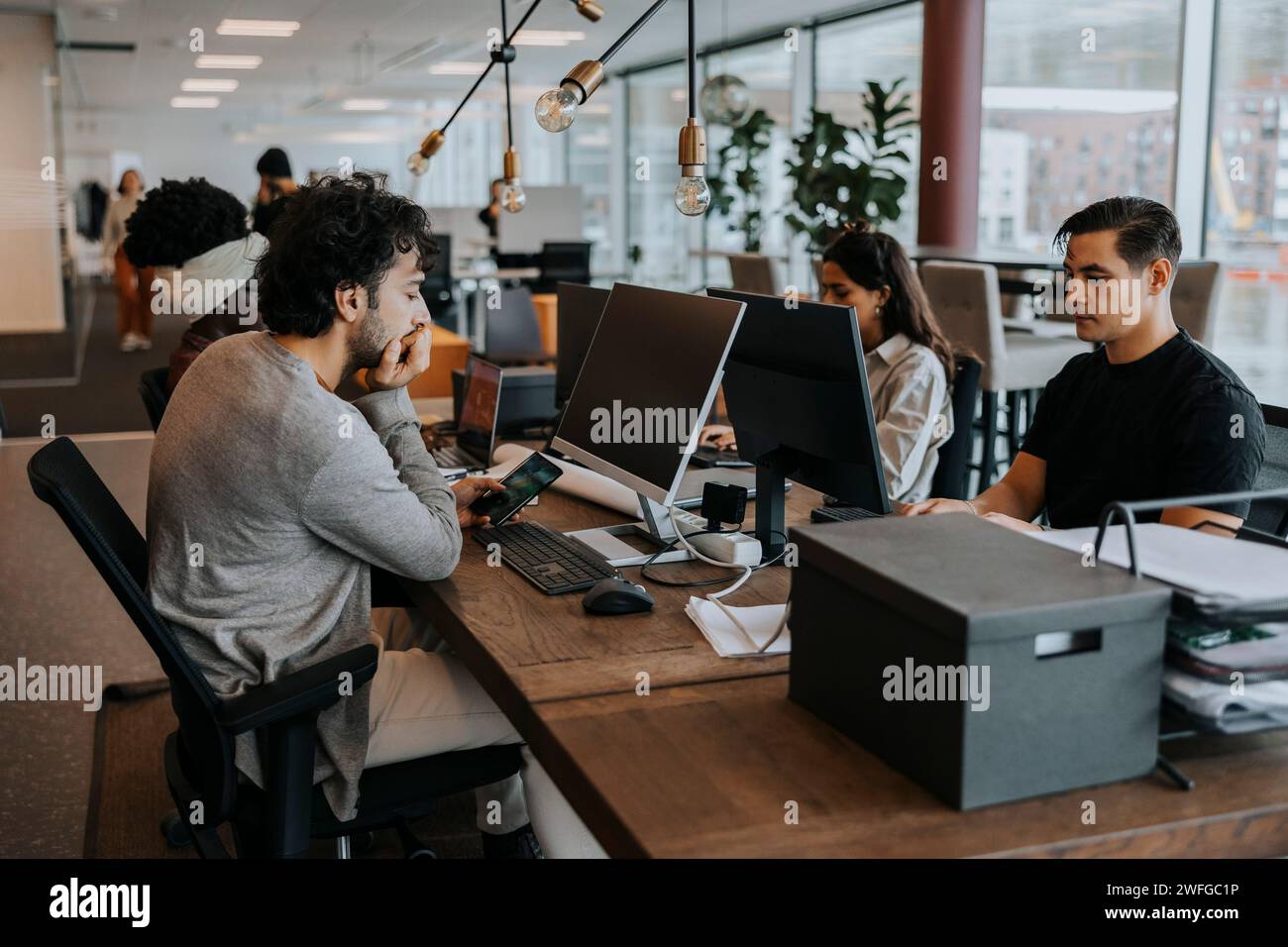 Multiracial colleagues sitting at desk working in corporate office Stock Photo