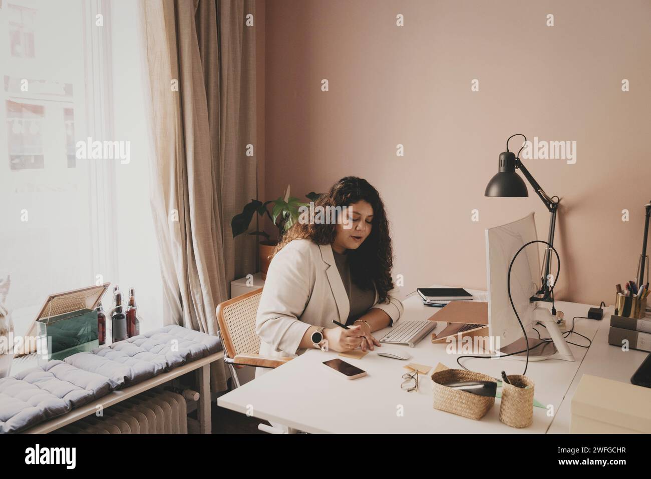 Young businesswoman working while sitting at desk in office Stock Photo