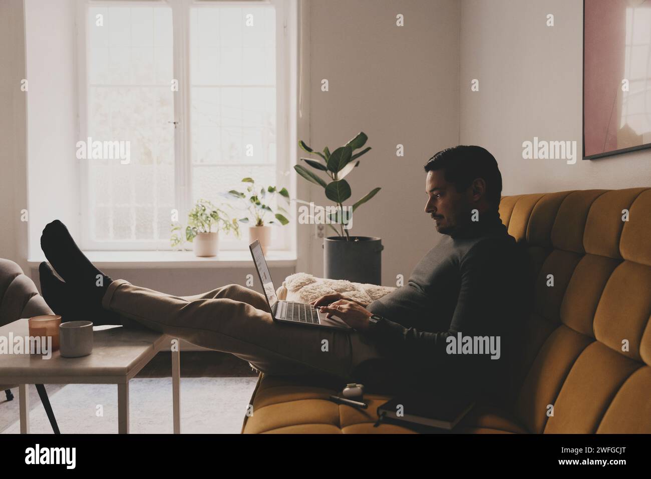 Businessman using laptop while sitting on sofa at office Stock Photo