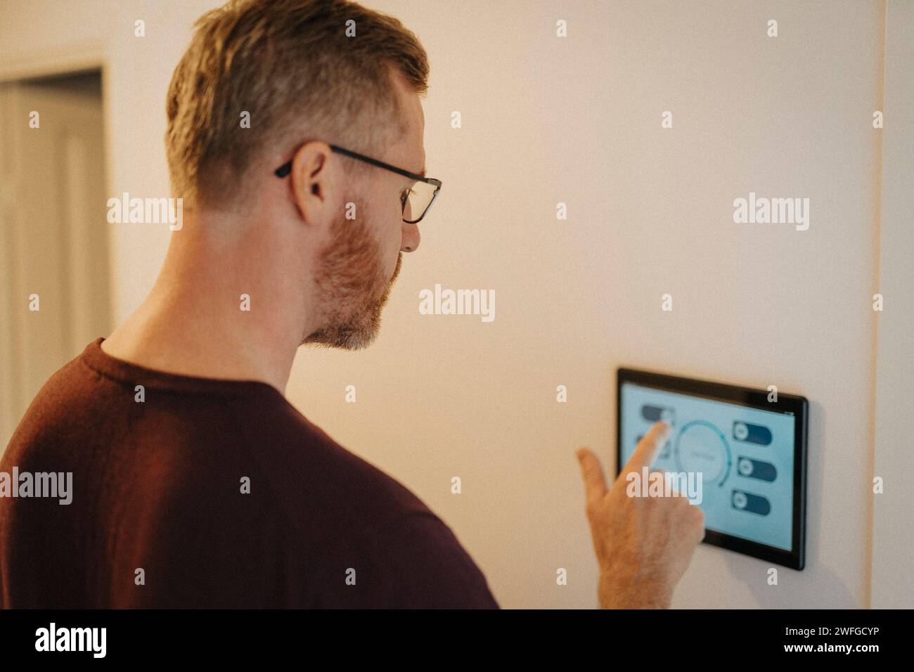 Mature man using digital tablet mounted on wall at smart home Stock Photo