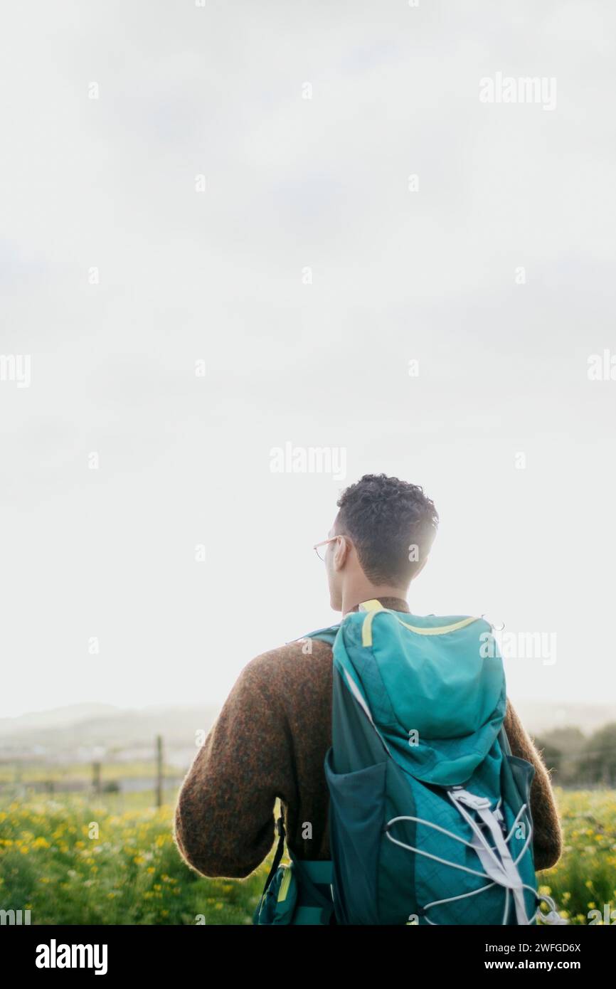 Rear view of man with backpack hiking under sky Stock Photo