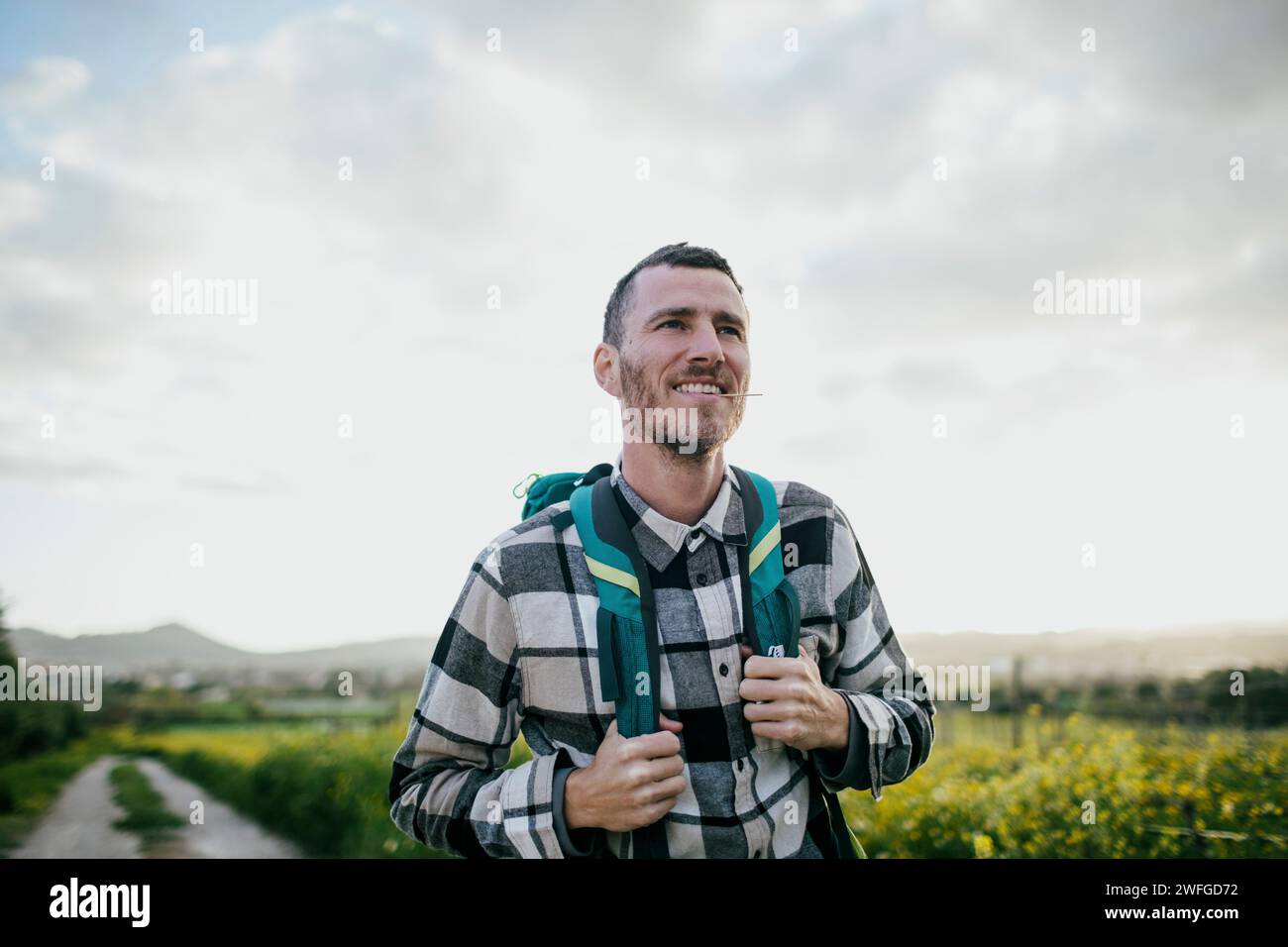 Smiling mature man with backpack hiking under sky Stock Photo