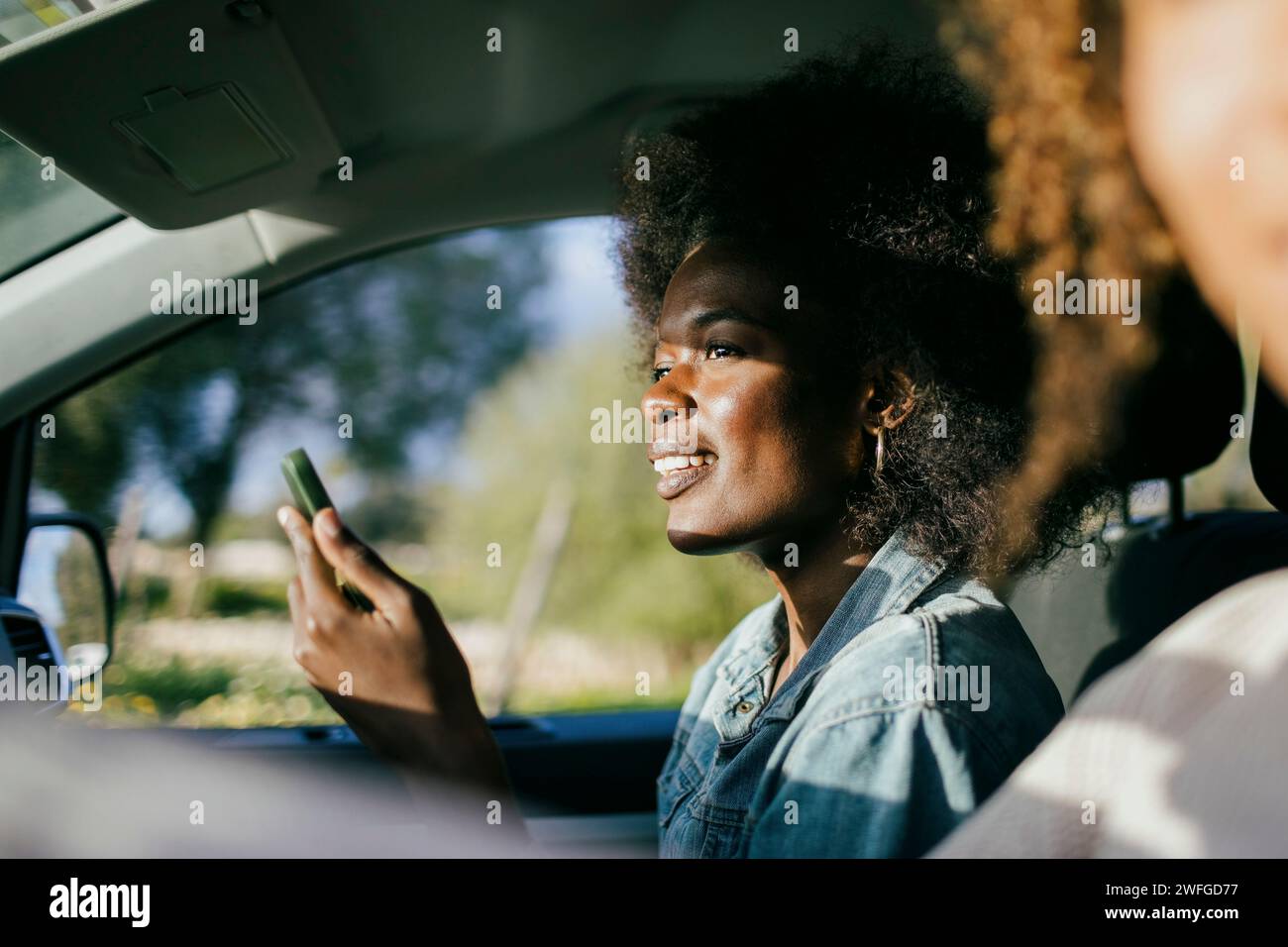 Smiling young woman using smart phone in car Stock Photo