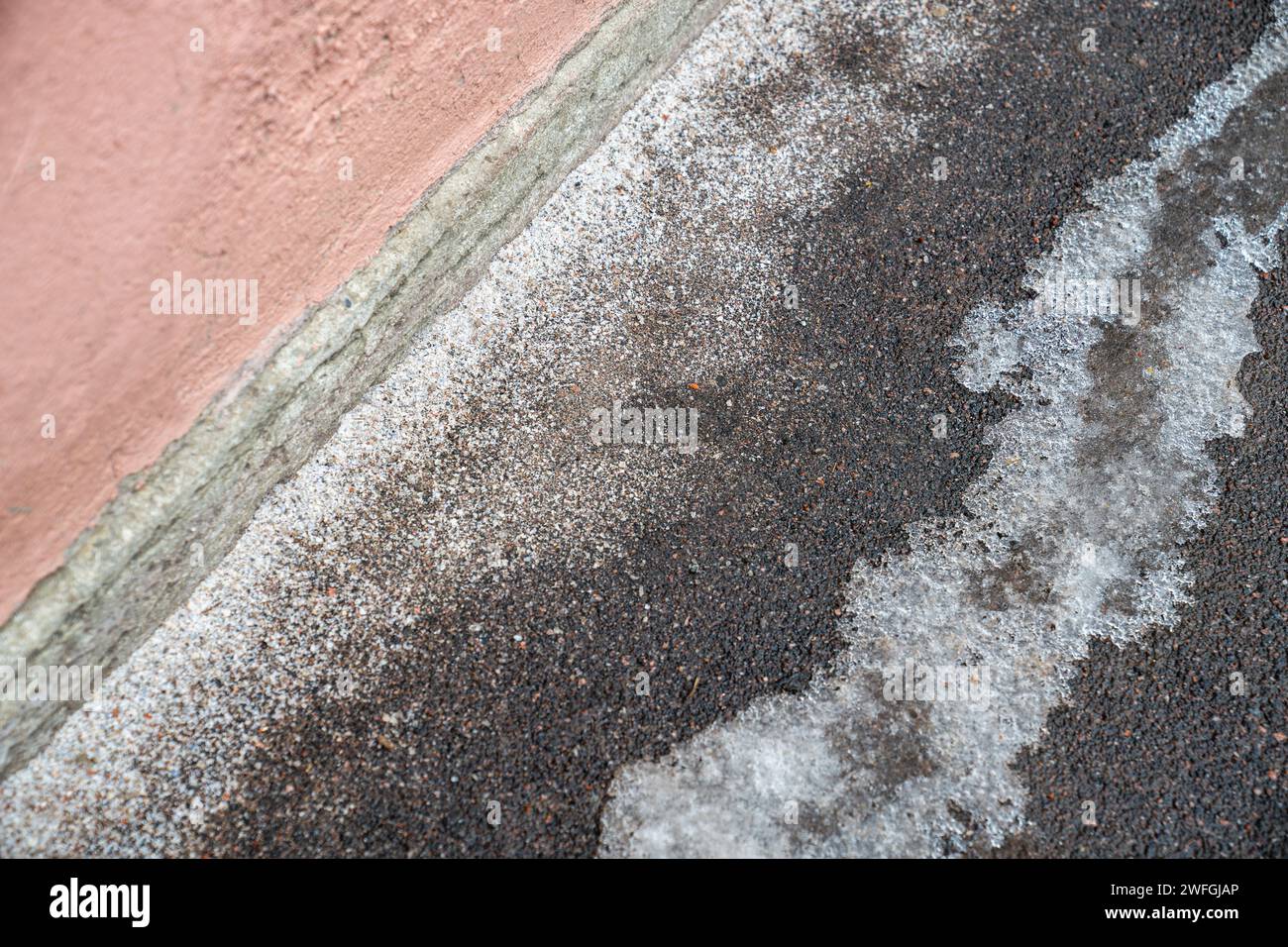 Deicing chemicals on pavement in winter. Salt grains on icy sidewalk