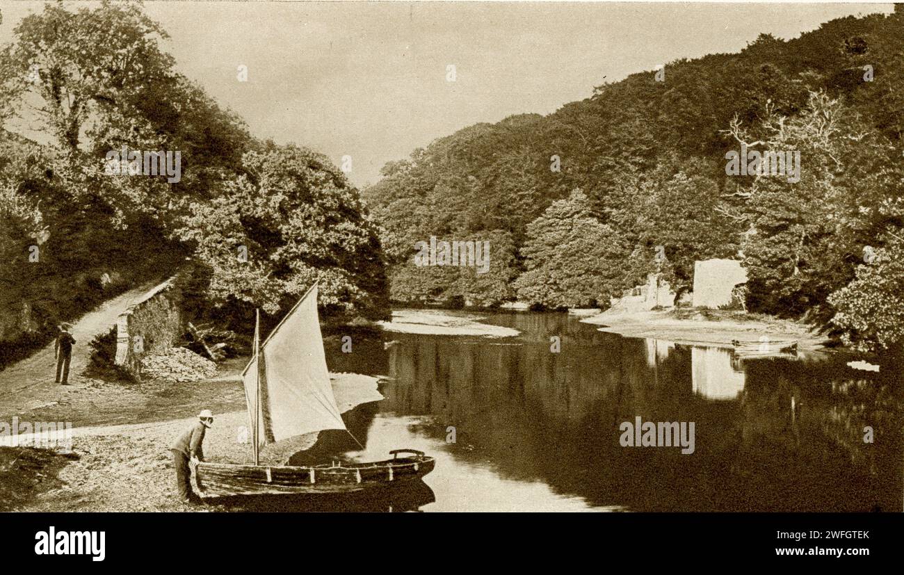 Photograph of fisherman and his boat at  Old Mill Creek,  River Dart, near the Royal Navy College, Dartmouth.  From the book Glorious Devon.  by S.P.B. Mais, published by London Great Western Railway Company, 1928. The photo is probably older, from around 1910. Stock Photo