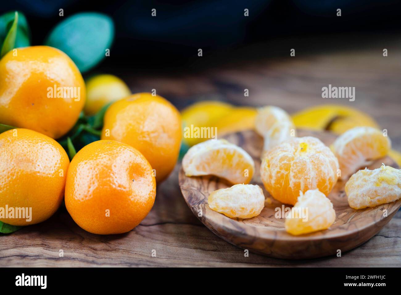 Calamondin, Calomondin, Camalmansi (Citrus madurensis, Citrofortunella microcarpa, Citrus fortunella, Citrus mitis), Fruit on the table, partly peeled Stock Photo