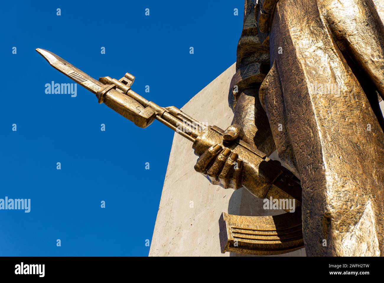 Low-angle view of a soldier statue holding a gun in Maqam Echahid monument against a blue sky. Stock Photo