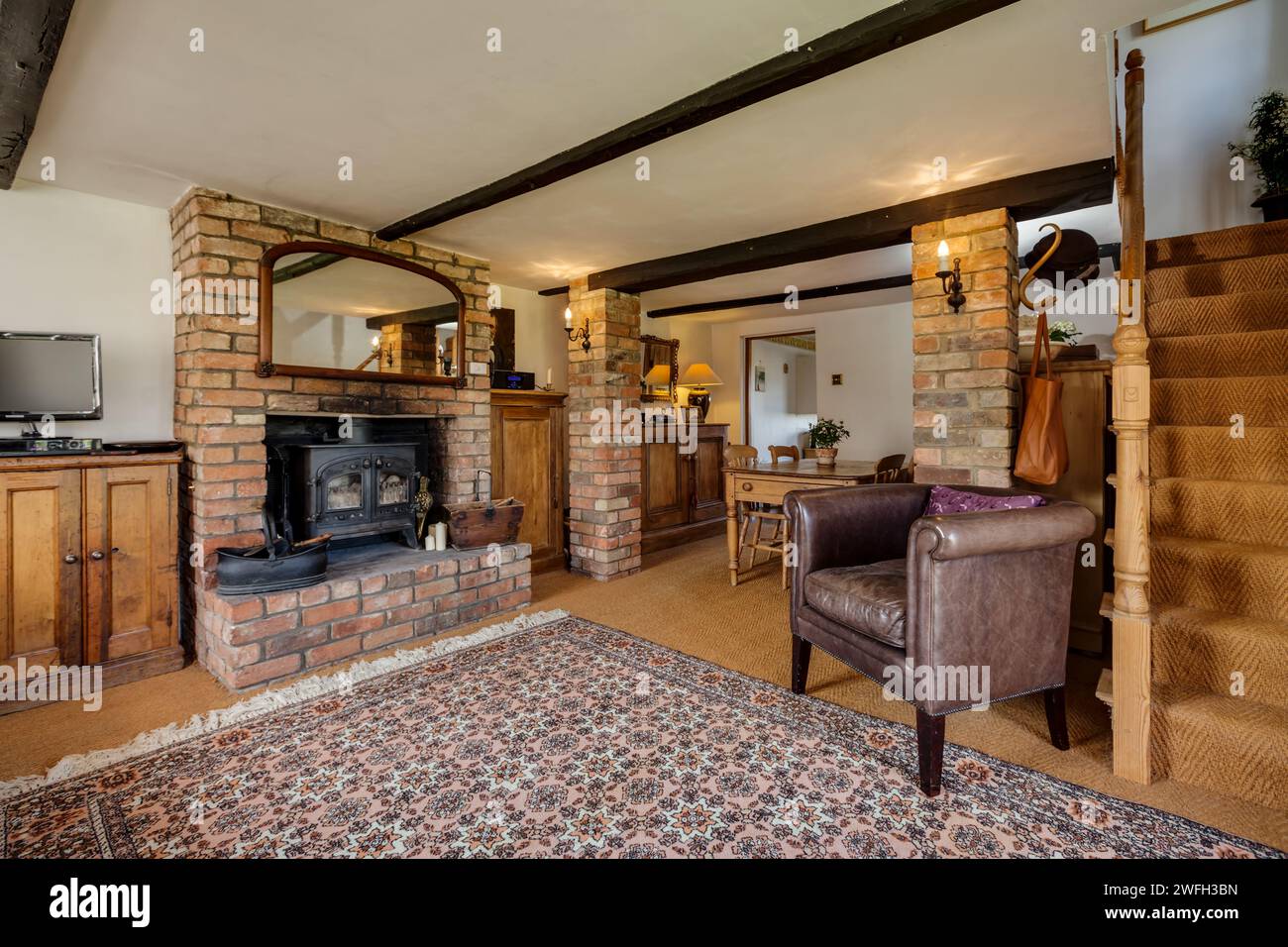 Boxworth, England - March 17 2016: Traditional furnished cottage living room with feature fireplace and woodburning stove Stock Photo