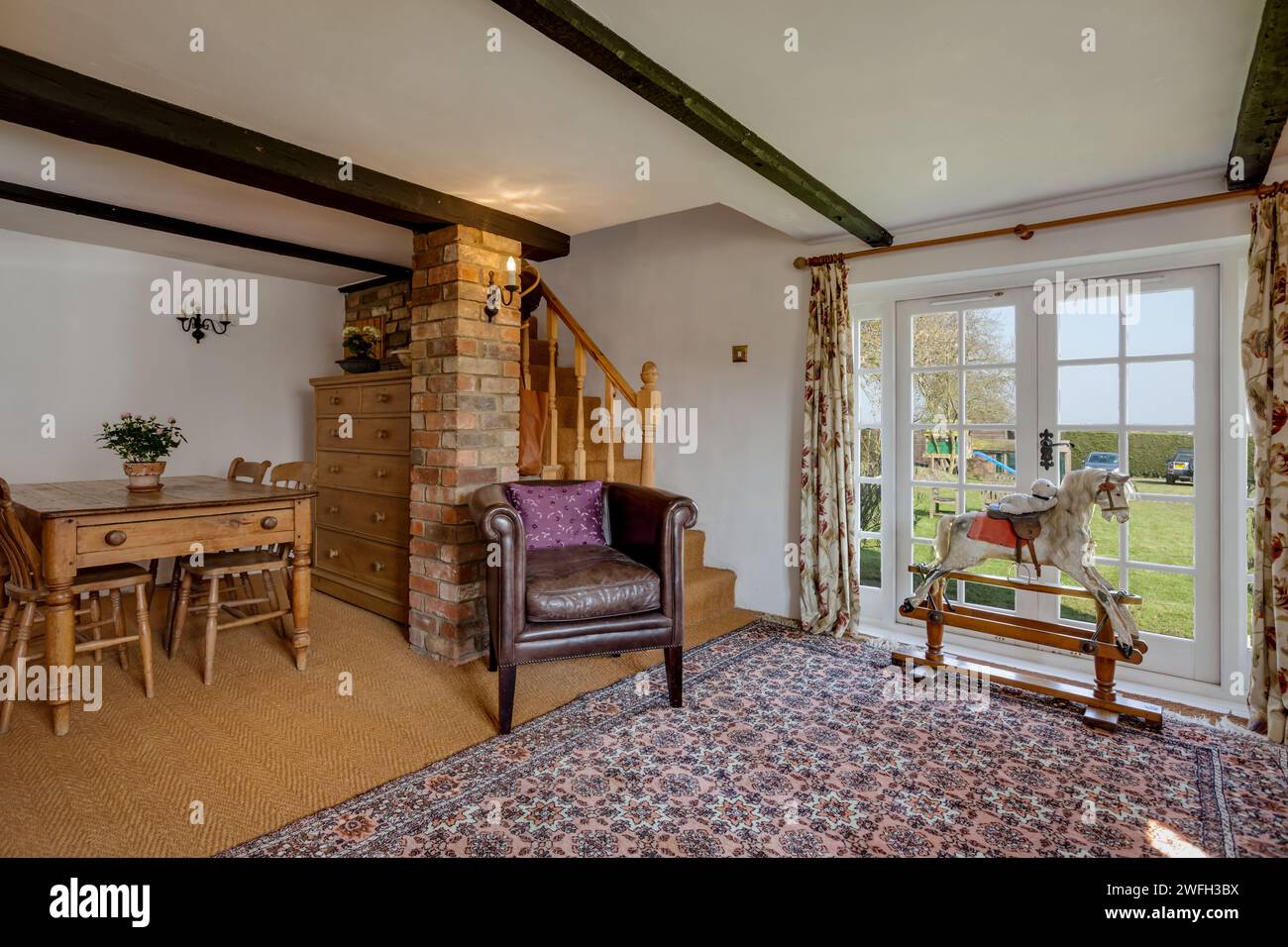 Boxworth, England - March 17 2016: Traditional furnished cottage living room with rocking horse Stock Photo