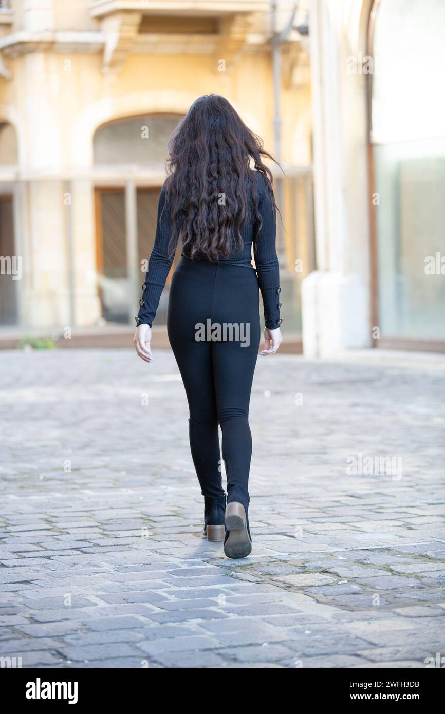 Rear view of woman in black walking away outdoors Stock Photo - Alamy