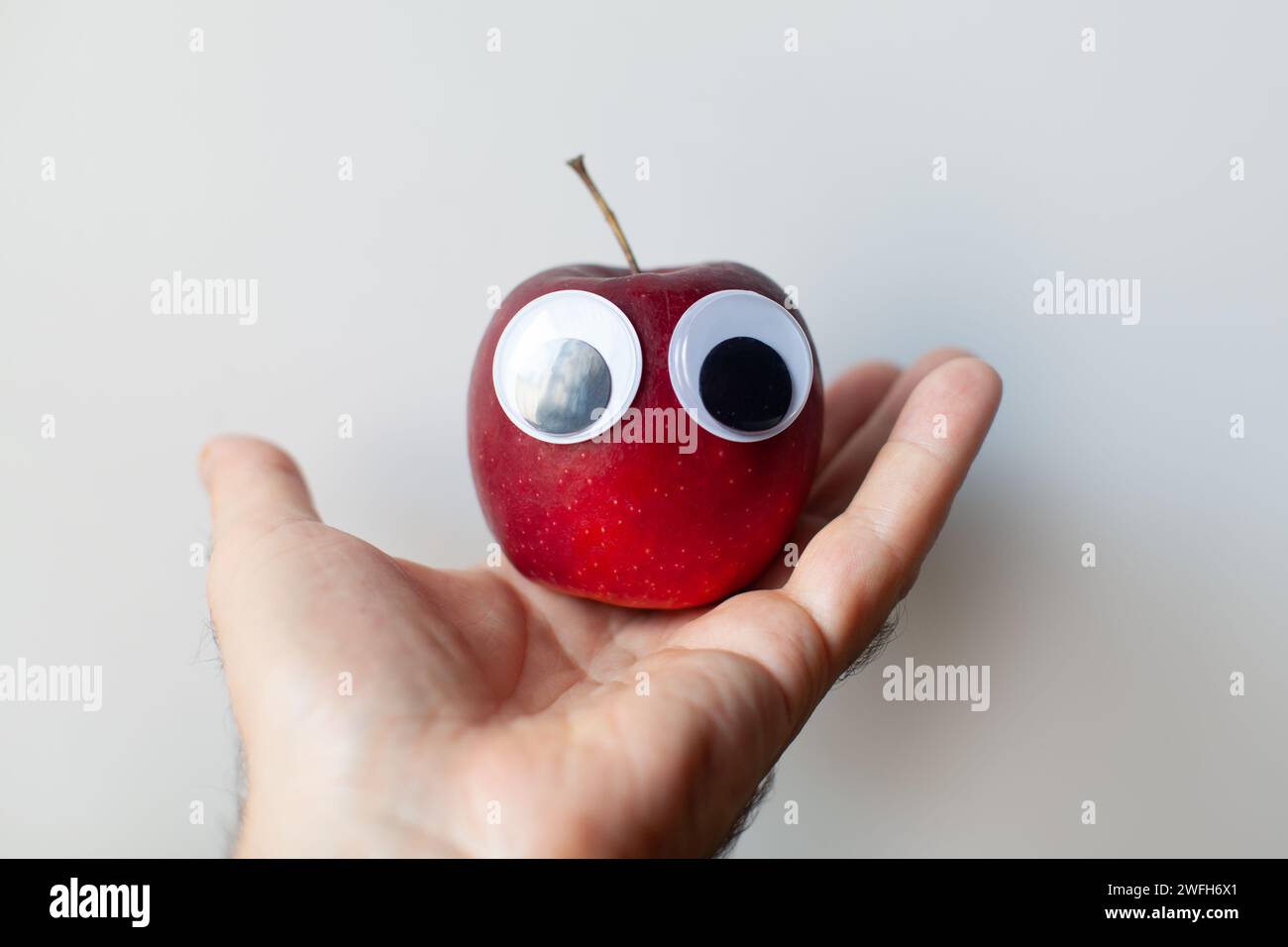 red apple with eyes in palm Stock Photo - Alamy