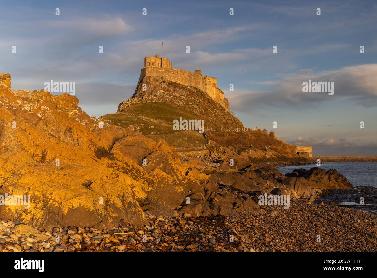 Sunset golden light over Lindisfarne Castle, Holy Island, Berwick upon Tweed, Northumberland, UK Stock Photo