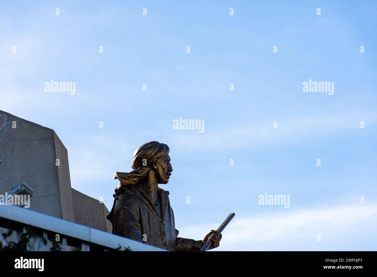 Low-angle view of a soldier statue holding a gun in the Maqam Echahid monument against a blue sky. Stock Photo