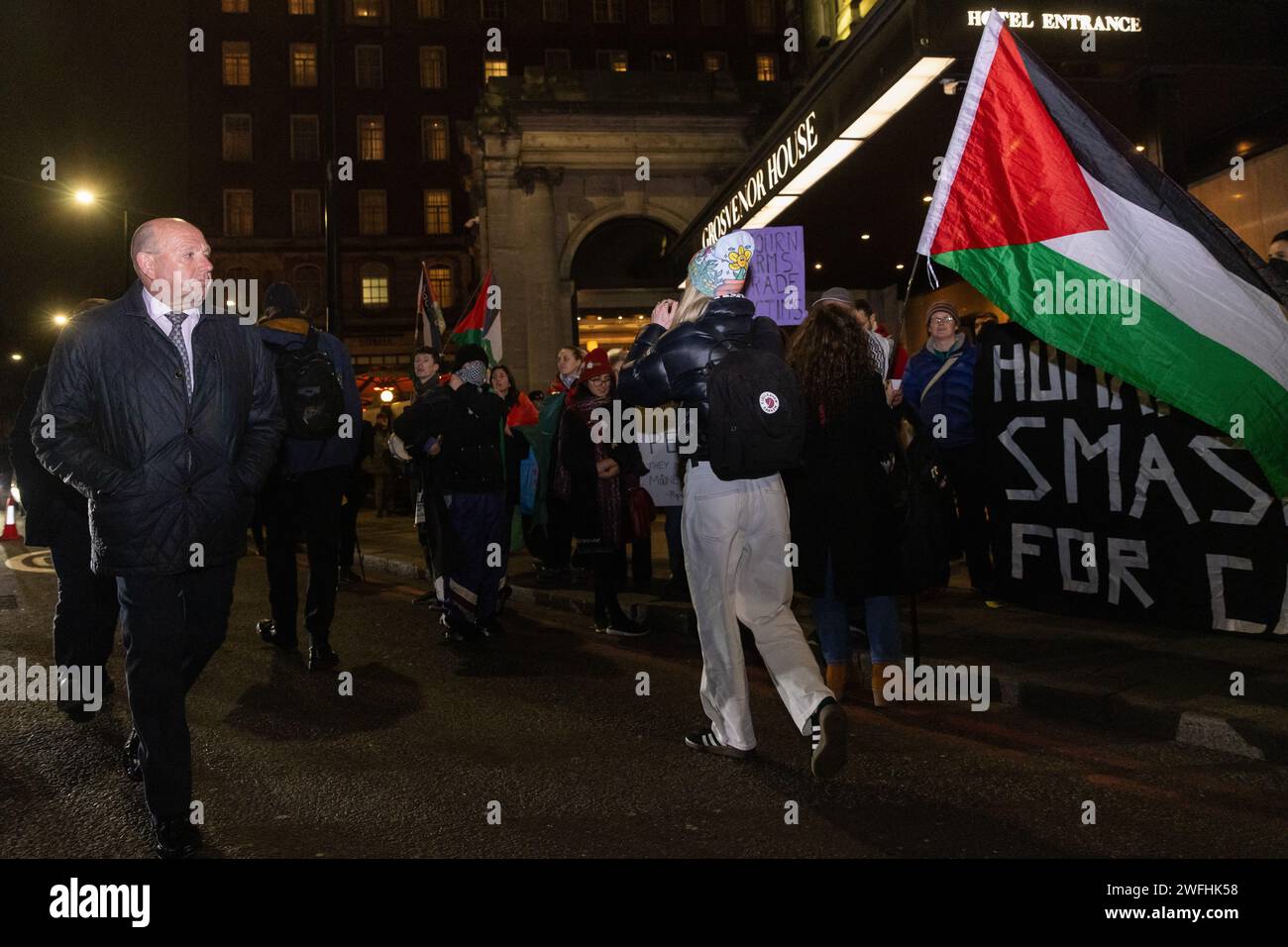 London, UK. 30th January, 2024. A guest arriving at the JW Marriott Grosvenor House Hotel for the ADS Annual Dinner encounters a protest by campaigners against the arms trade. The ADS Annual Dinner brings together representatives of companies from the UK's aerospace, defence, security and space industries. Sponsors of the event include BAE Systems which supplies components for F-35 combat aircraft used by Israel during its invasion of Gaza. Credit: Mark Kerrison/Alamy Live News Stock Photo