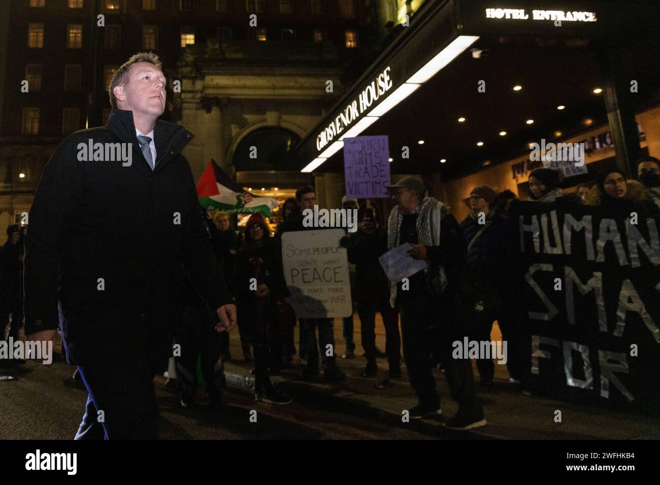 London, UK. 30th January, 2024. A guest arriving at the JW Marriott Grosvenor House Hotel for the ADS Annual Dinner encounters a protest by campaigners against the arms trade. The ADS Annual Dinner brings together representatives of companies from the UK's aerospace, defence, security and space industries. Sponsors of the event include BAE Systems which supplies components for F-35 combat aircraft used by Israel during its invasion of Gaza. Credit: Mark Kerrison/Alamy Live News Stock Photo