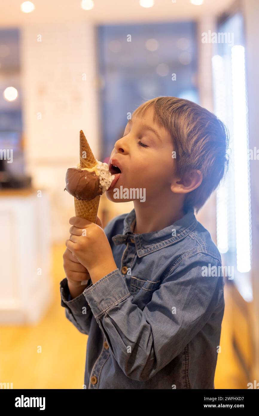 Cute sweet boy, child, eating ice cream in a small ice cream shop wintertime Stock Photo