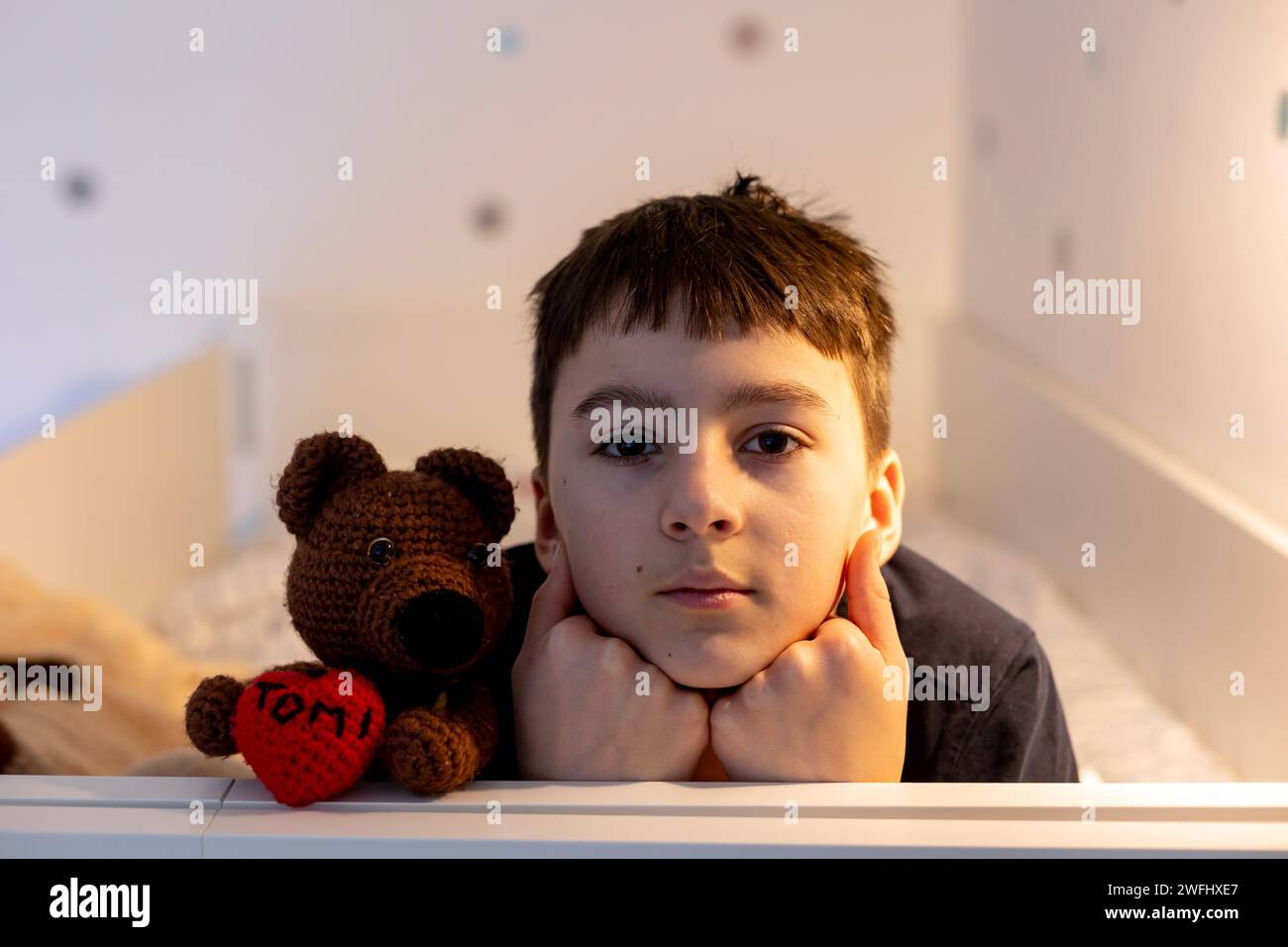 Portrait of a teenage boy in bedroom with some toys in bed Stock Photo