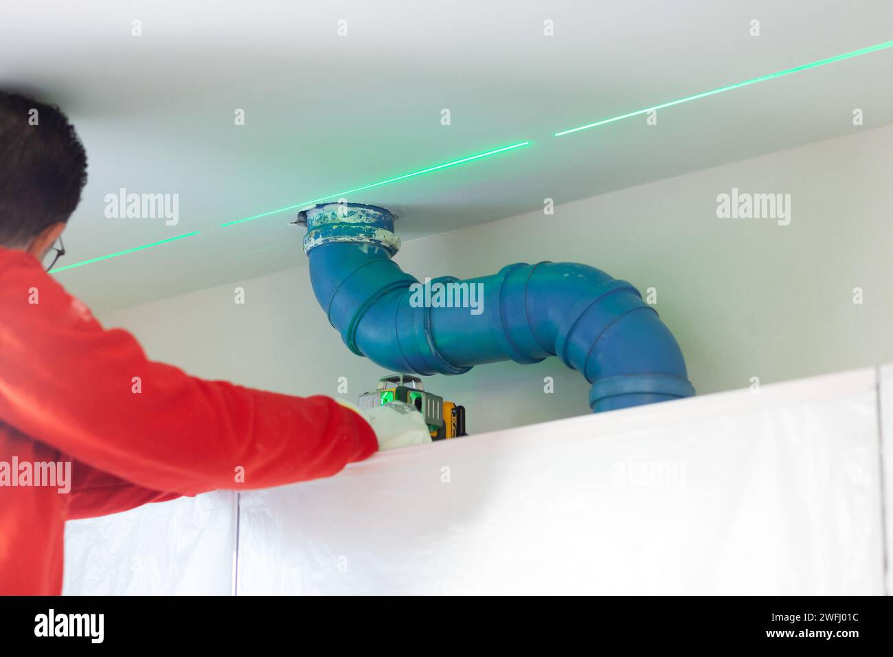 A plasterer takes measurements with a laser level to create a wall