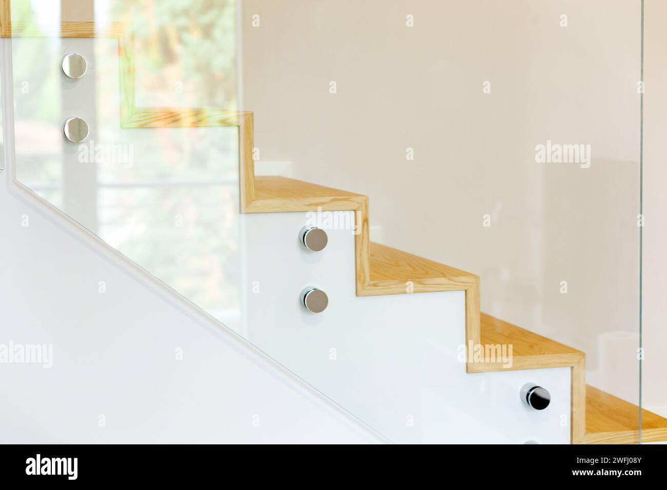 Staircase covered in oak parquet with tempered glass balustrade and chromed pins. Stock Photo