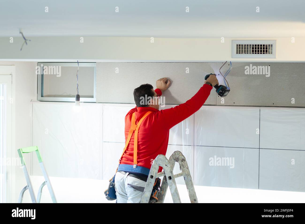 Plasterboard worker installs a plasterboard wall on the kitchen