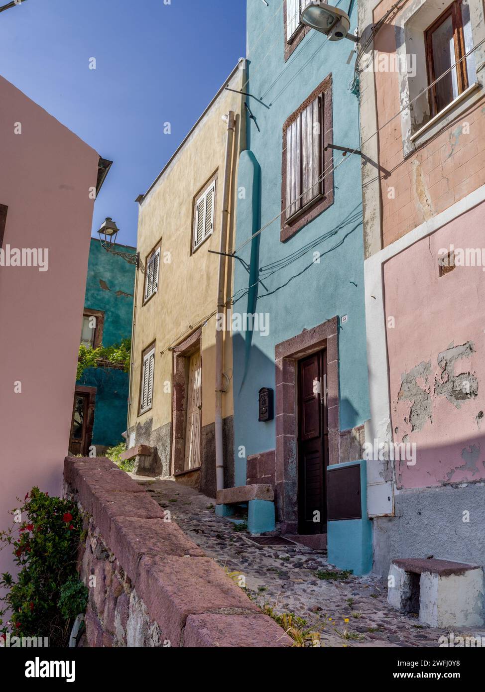 Sloped cobblestone walkway along buildings in the Town of  Bosa, Sardinia, Italy Stock Photo