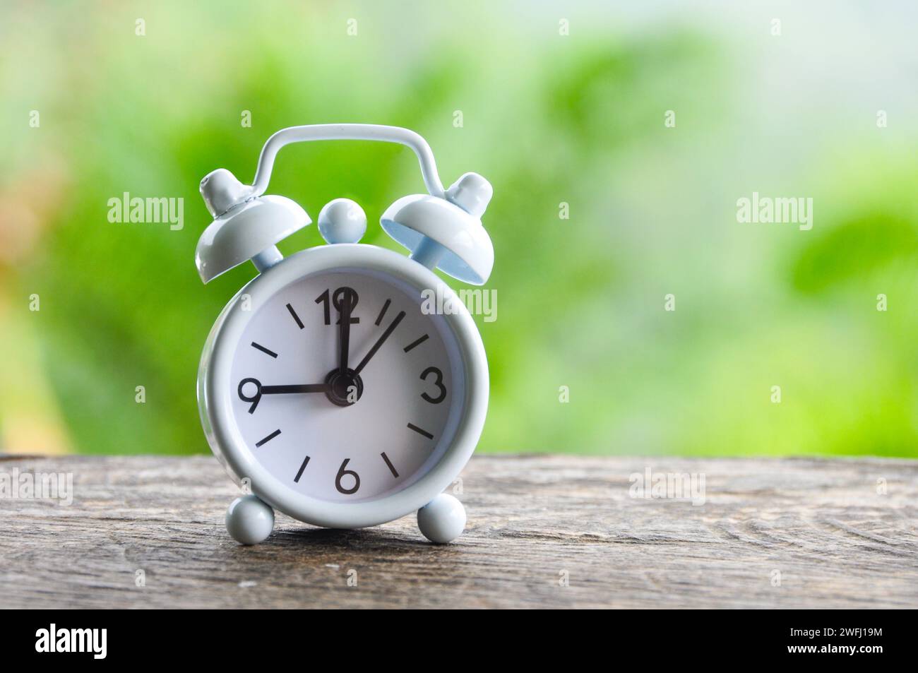 Table alarm clock pointing at 9 am. Time concept and copy space Stock