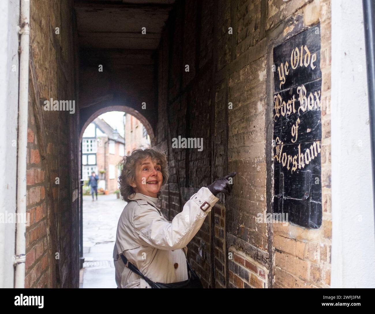 Visitor looks at Ye Olde Post Box set in a wall off Market Square Horsham , West Sussex , England UK Stock Photo