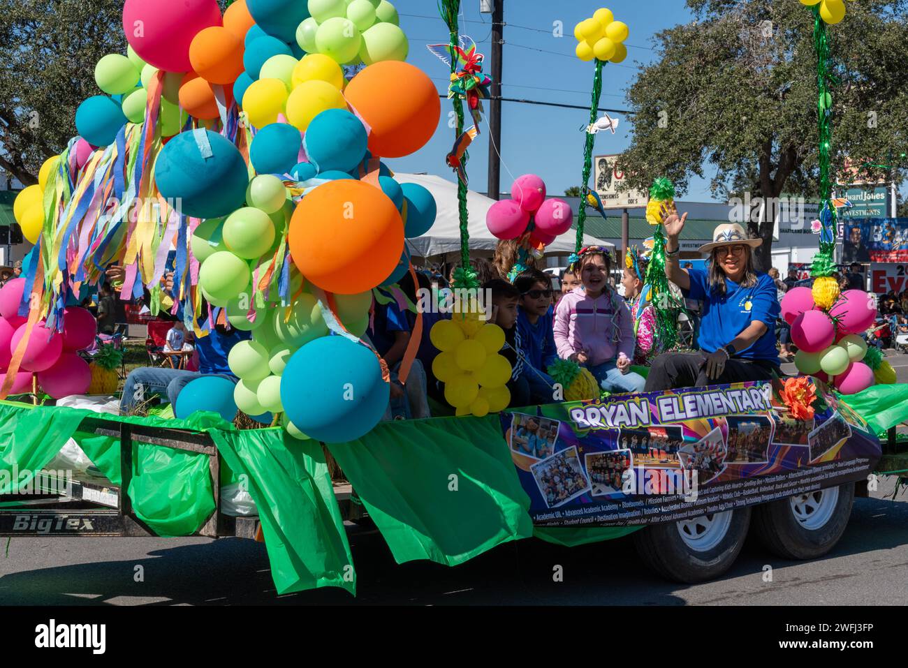 Parade float with balloons and people waving in 92nd Annual Texas