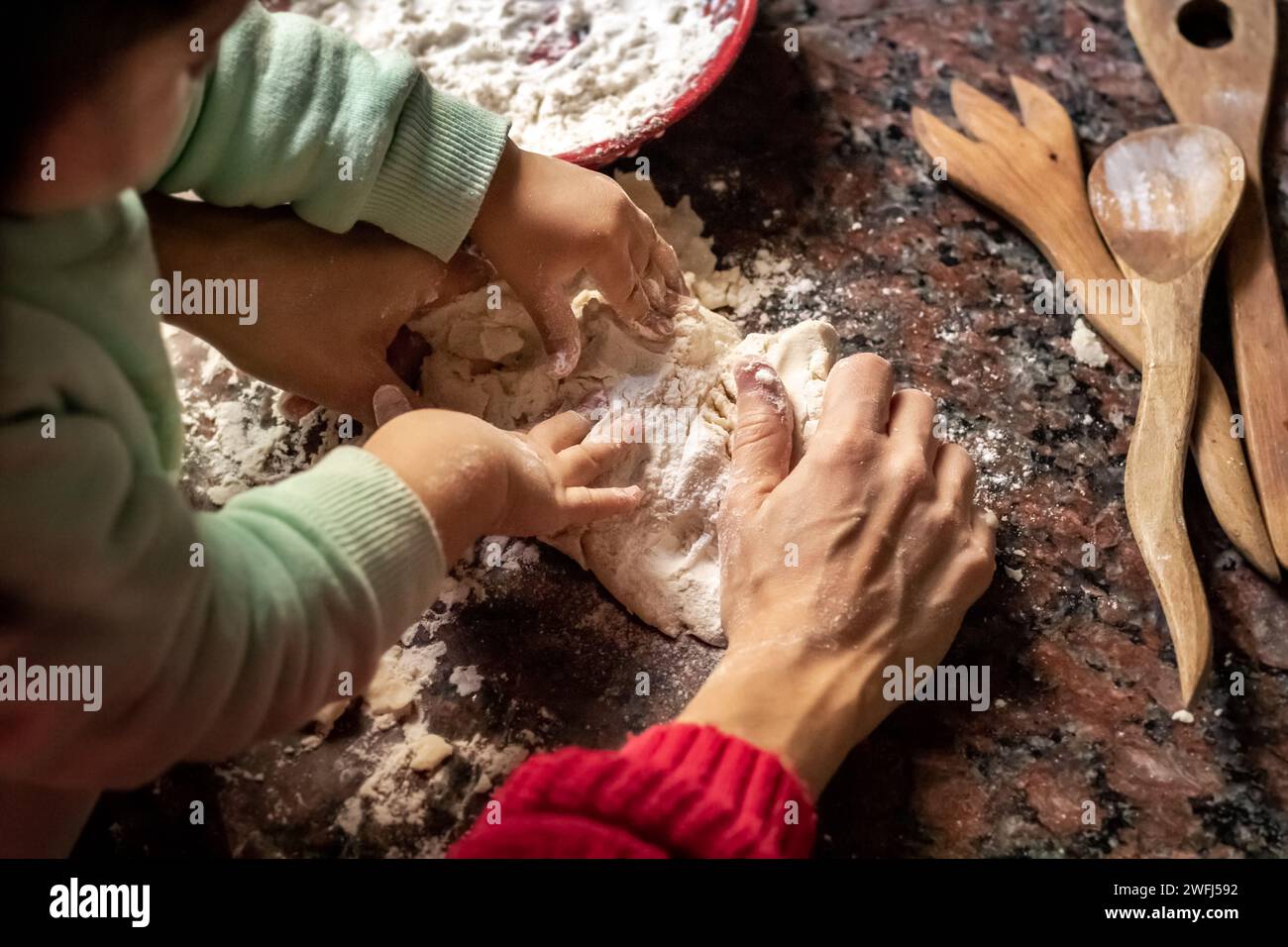 A woman and child collaborate in the kitchen, kneading dough Stock Photo