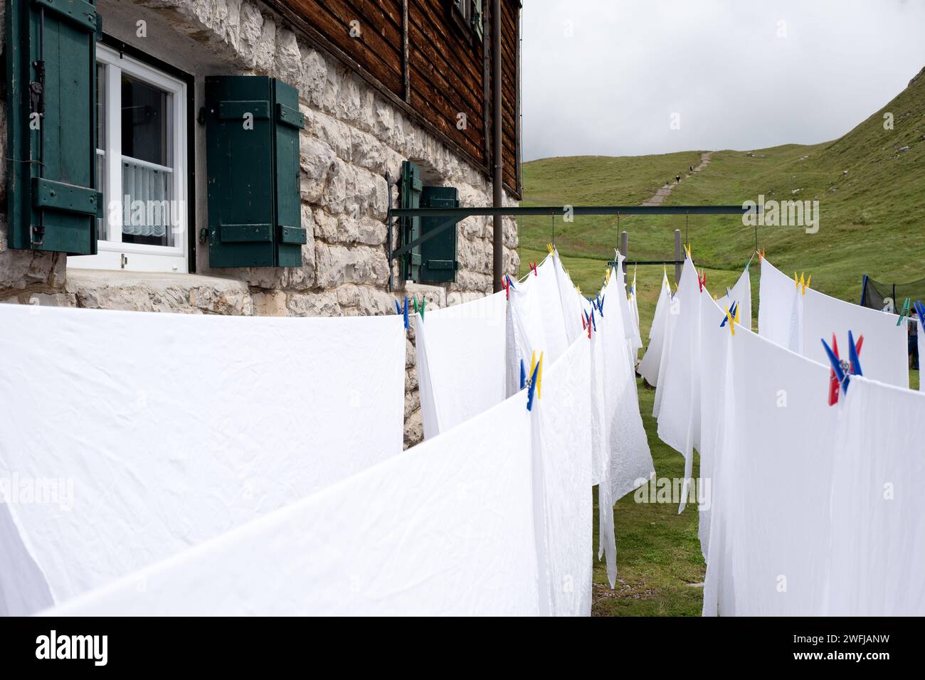 White sheets hang out to dry outside a mountain retreat of the Dolomites mountains Stock Photo