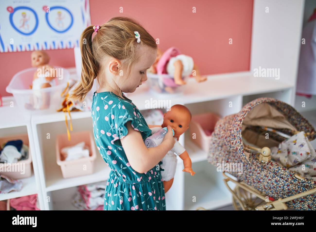 Adorable preschooler girl playing with baby dolls in nursery role