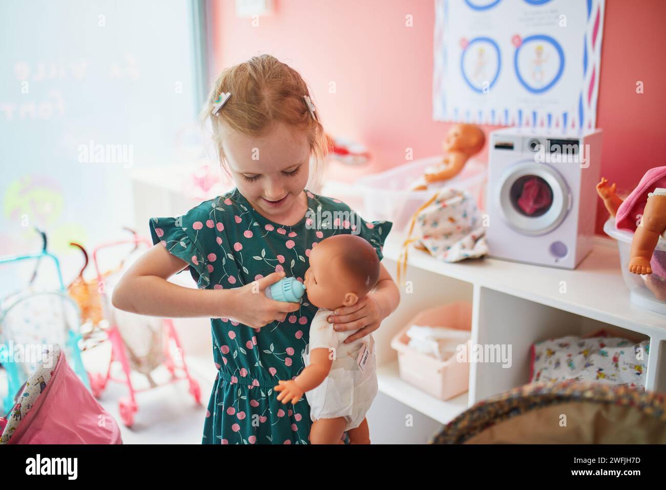 Adorable preschooler girl playing with baby dolls in nursery role