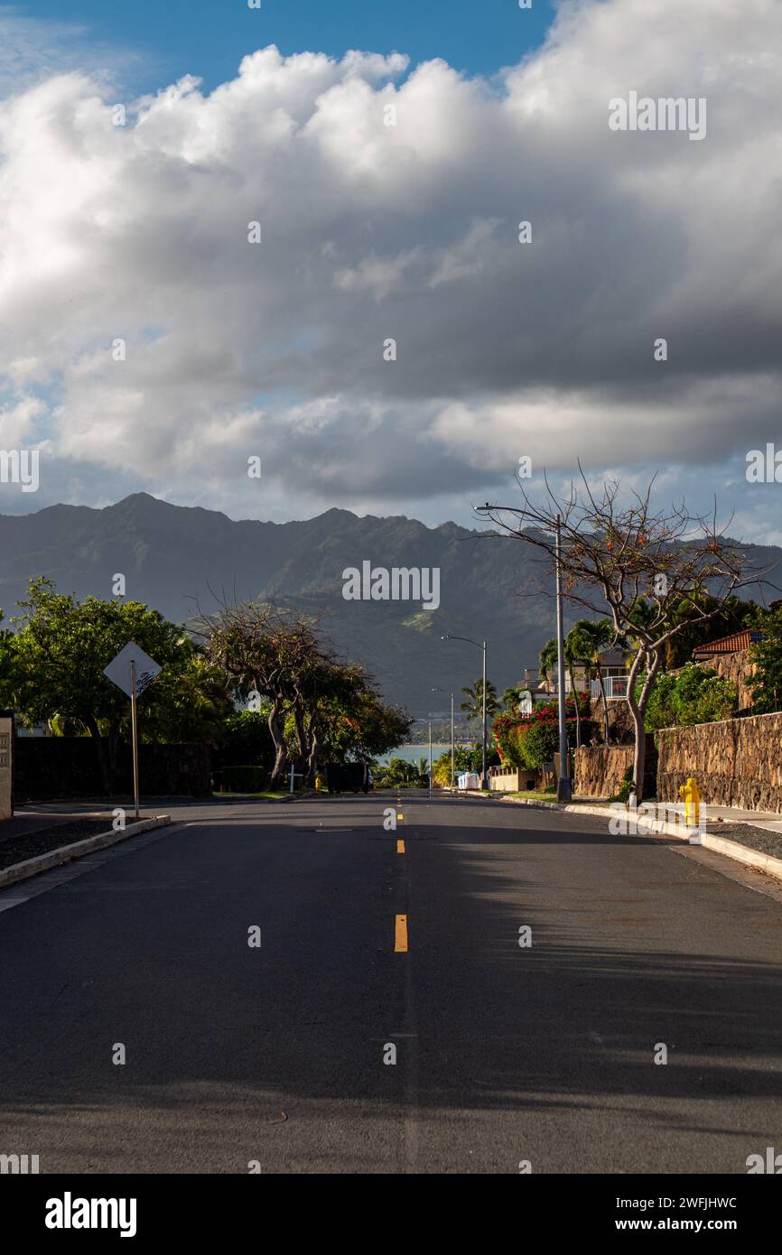 A Hawaiian neighborhood street with mountains in the background - Honolulu, Hawaii Stock Photo